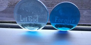 Two blue glass stones with inscriptions 'Let God' and 'Forgive'.