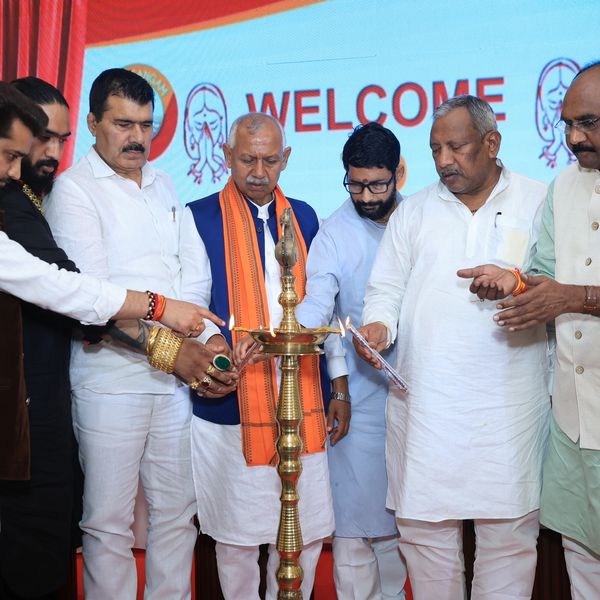 Group lighting a ceremonial lamp at a formal event with a welcome backdrop.