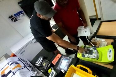 Two men examining electronic equipment and manuals indoors.