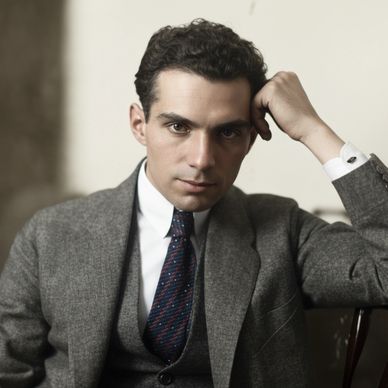 Young man in a gray suit and tie sitting thoughtfully.