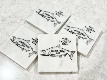 Marble coasters with a fish and "The Thirsty Gill Amateur Fishing Club" logo.
