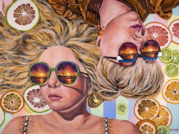 Deux femmes allongées avec des lunettes de soleil et des tranches d'agrumes.