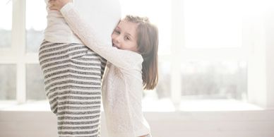 young girl hugging pregnant mum