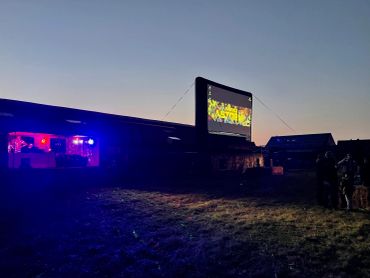 Outdoor movie screening at dusk with people gathered.
