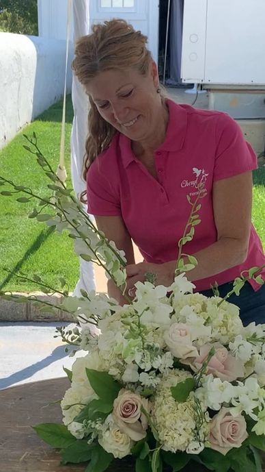 Woman arranging a beautiful white and pale pink floral bouquet outdoors.