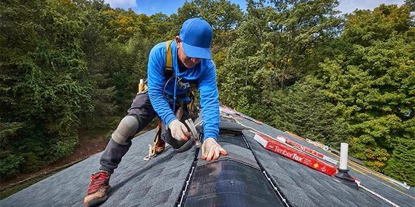 Roofer installing solar shingles on a roof.