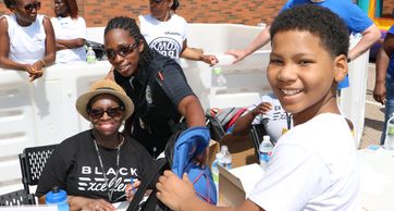 A volunteer handing a child a backpack at the backpack giveaway 