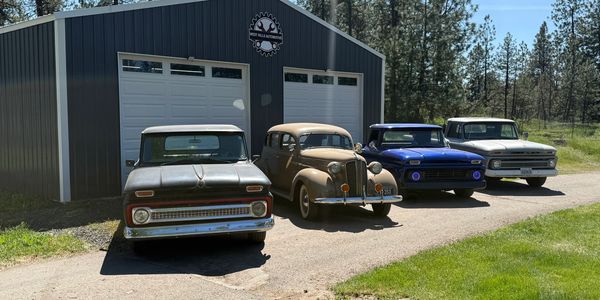 Four vintage vehicles parked outside a garage.