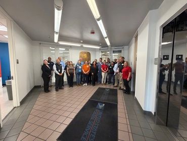 Group photo of people standing in an office hallway near elevators.