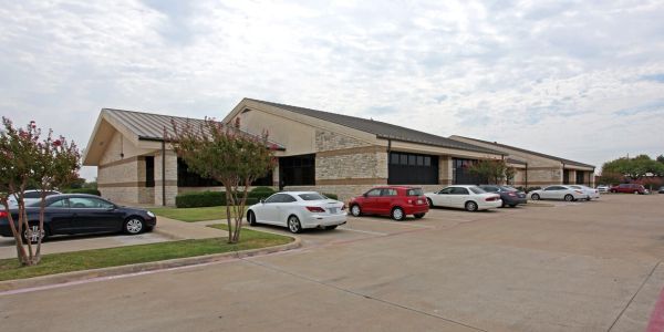 Parking lot with cars outside a commercial building on a cloudy day.