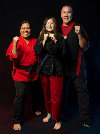 Three martial artists posing confidently in uniforms.