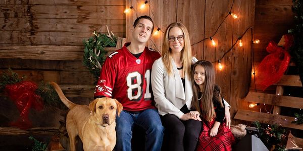 Christmas family photo with mother, father, child, and dog. 