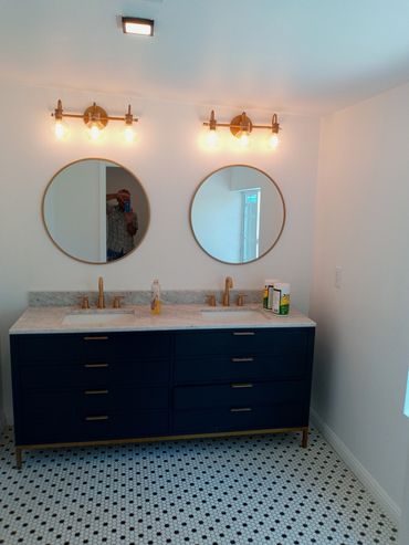 Double vanity bathroom setup with round mirrors and brass fixtures.