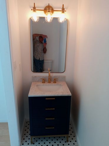 Small bathroom vanity with blue drawers and brass fixtures.