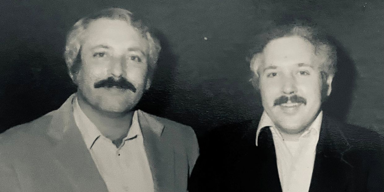 Two men with mustaches posing for a photo.