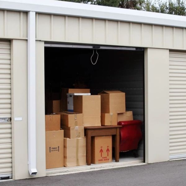Storage unit filled with cardboard boxes and a small red chair.