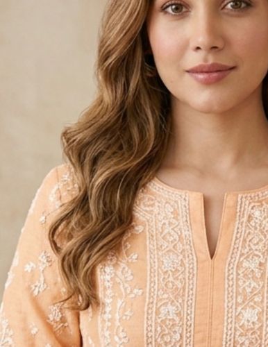 Woman in peach embroidered traditional attire with loose wavy hair.