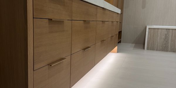 Modern wooden cabinet with white countertop and underlighting.