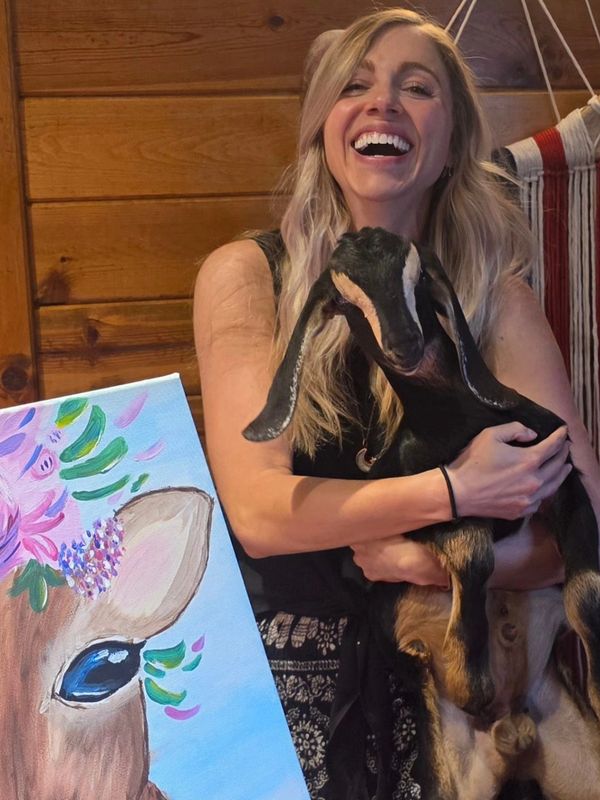 class member holding one of our baby goats at a painting with baby goats class!