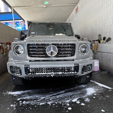 Mercedes-Benz G-Class covered in soap at a car wash station.