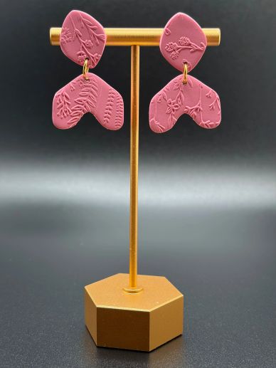 Pink embossed earrings on a gold stand.