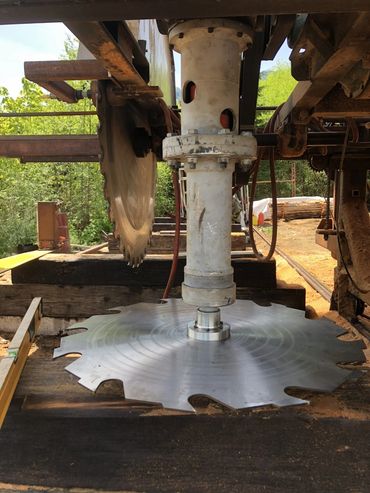 Large circular saw blades mounted on industrial woodcutting machinery outdoors.