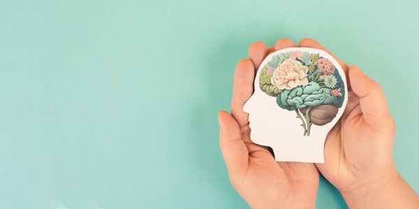 Hands holding a brain illustration with blooming flowers symbolizing mental growth.