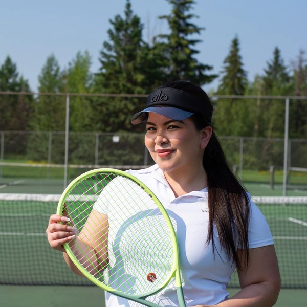 Woman posing with tennis racquet on court.