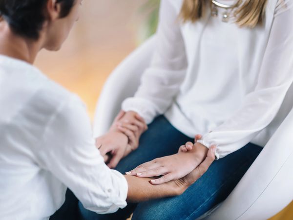 A compassionate person gently holds the hands of another, offering support.
