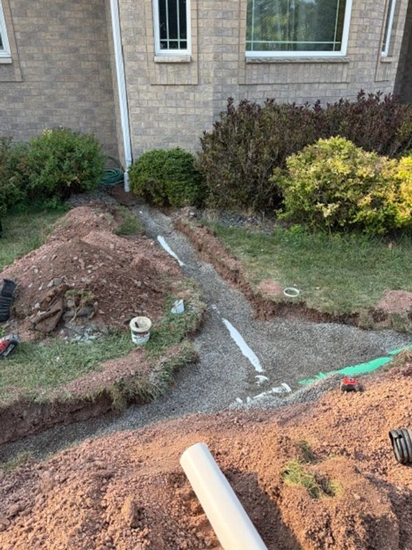 Trench excavation near house for pipe installation.