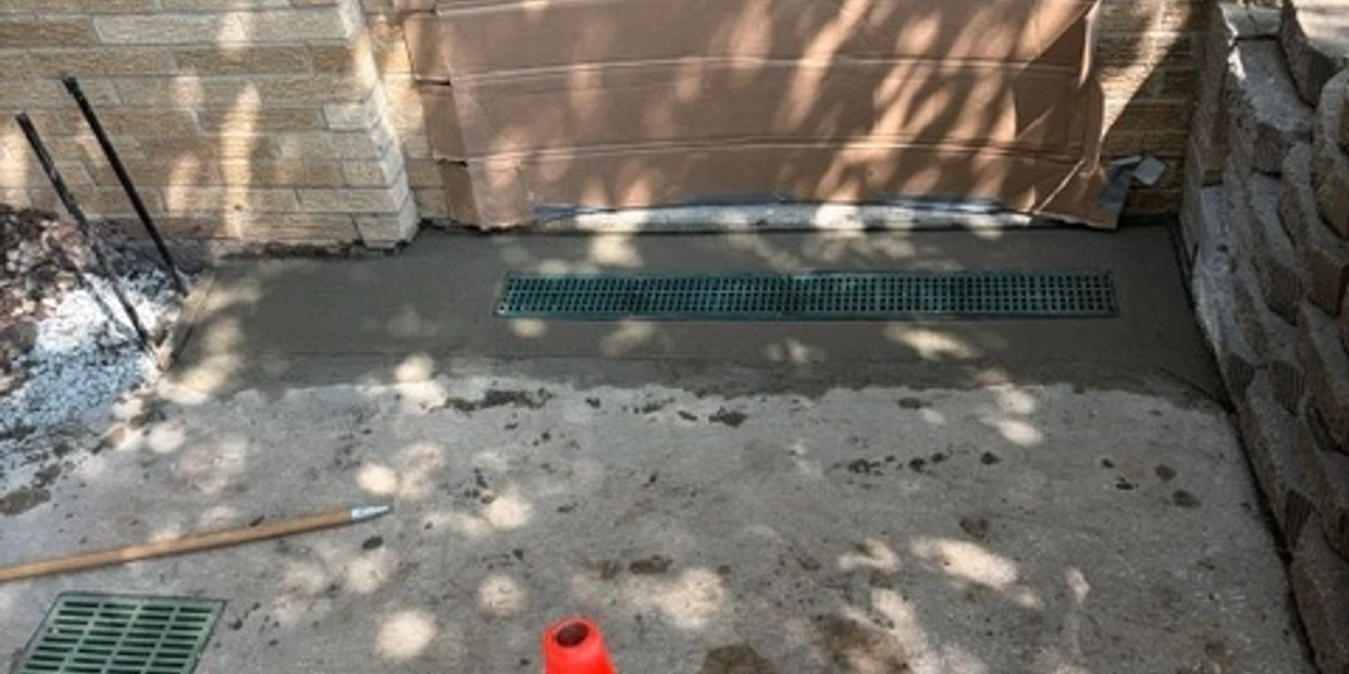 Freshly poured concrete with drainage grates in front of a door.