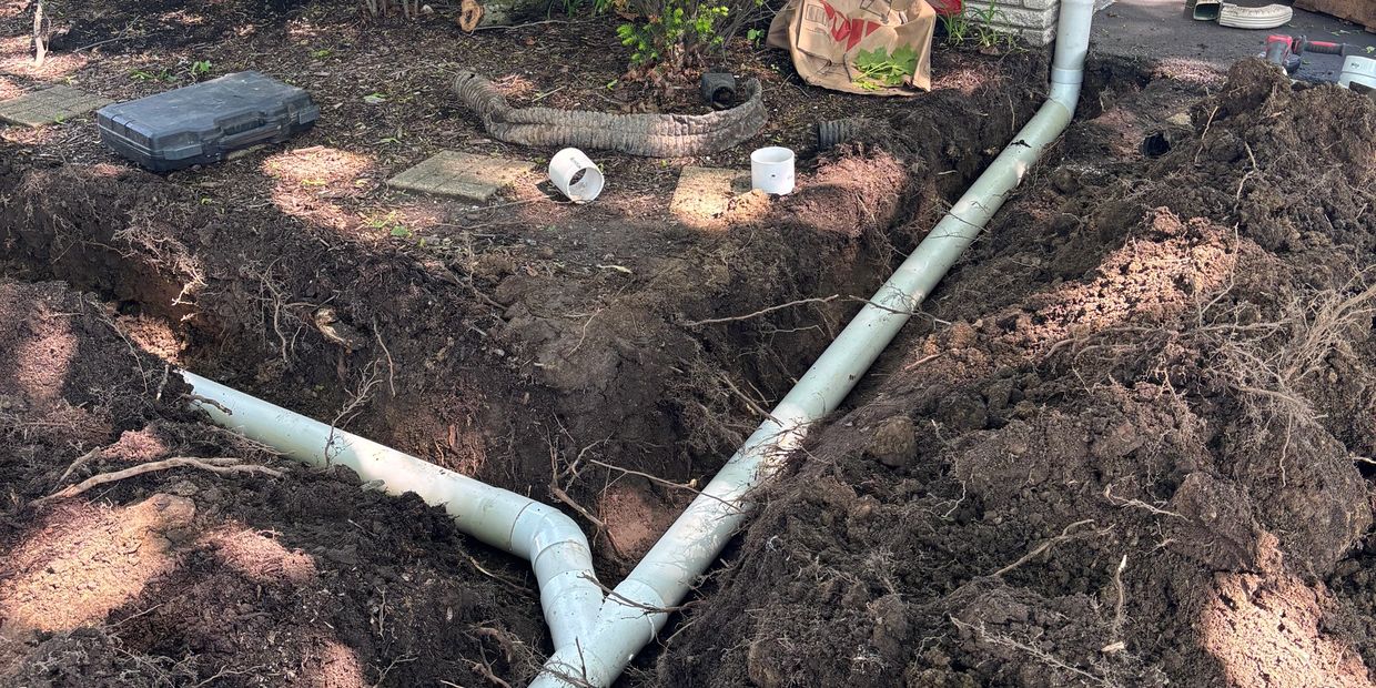 Underground pipe installation in a yard trench.