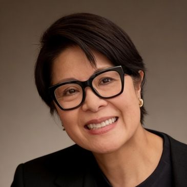 Smiling woman wearing large black glasses and a black jacket.