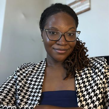 Smiling woman with glasses and braided hair.