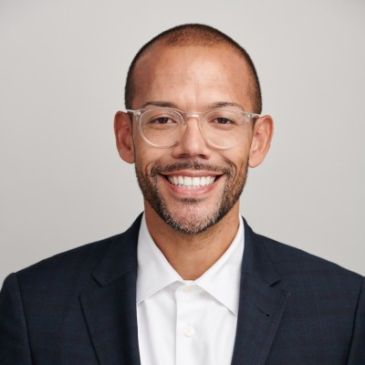 Smiling man in glasses and suit.