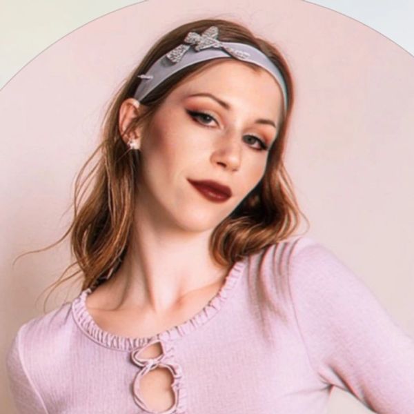 Woman with red lipstick and headband wearing a pink top.
