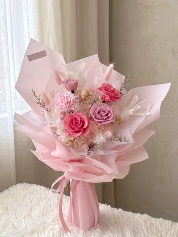 Elegant pink and purple floral bouquet wrapped in soft pink paper.