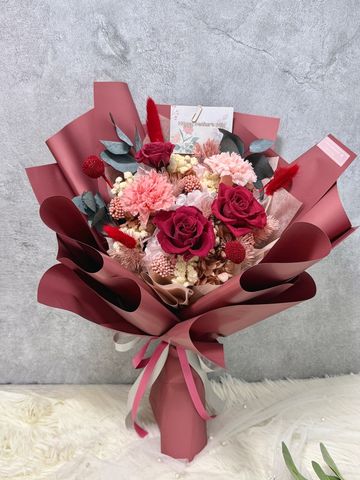 Elegant bouquet with red roses and pink flowers wrapped in deep red paper.