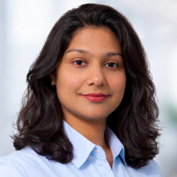 Confident woman with dark hair wearing a light blue shirt.