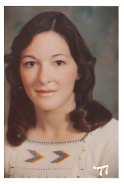 Portrait of a woman from 1977 with curled hair and a patterned top.