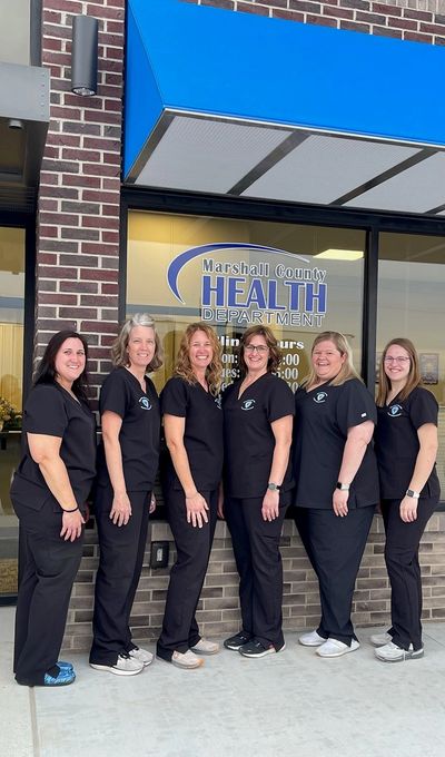 Six women in black scrubs stand outside Marshall County Health Department.