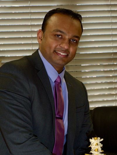 Man in suit smiling near window blinds.