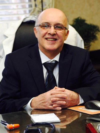 Smiling elderly man in suit sitting at desk.