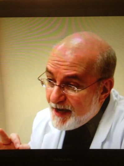 Older man with glasses speaking.