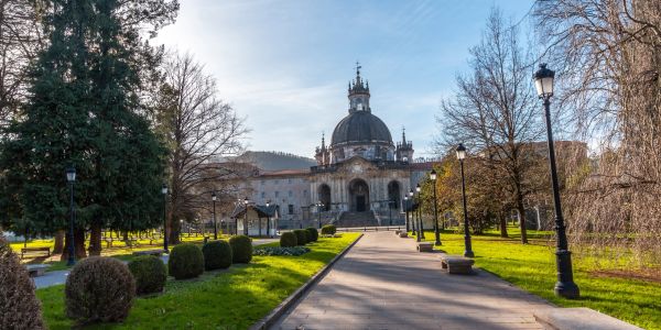 Historic building with dome at the end of a tree-lined pathway.