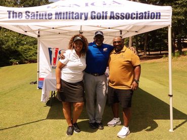 Three people posing under a golf association tent.