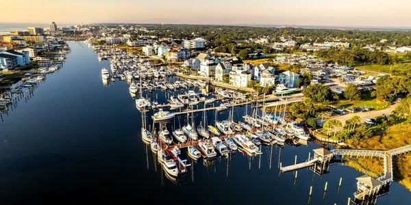 Aerial view of a marina with boats docked along a peaceful waterfront town.