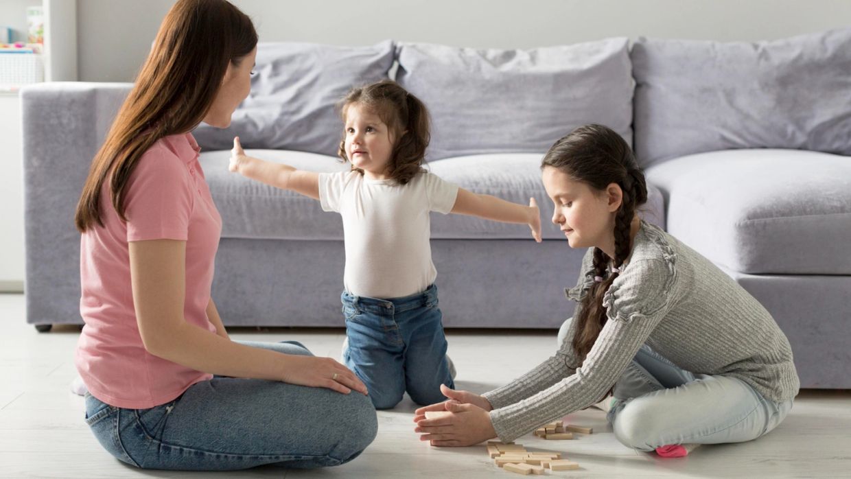 Mother and children playing on the floor near a couch.