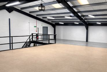 Empty industrial space with beige tile flooring and metal stairs.