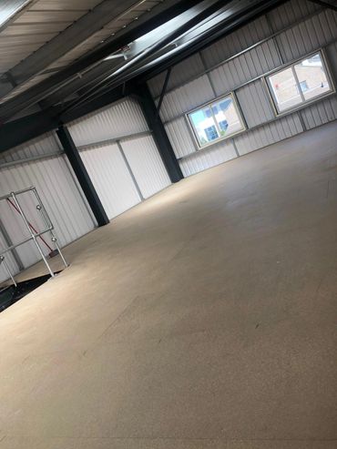 Empty industrial space with large windows and metal walls.